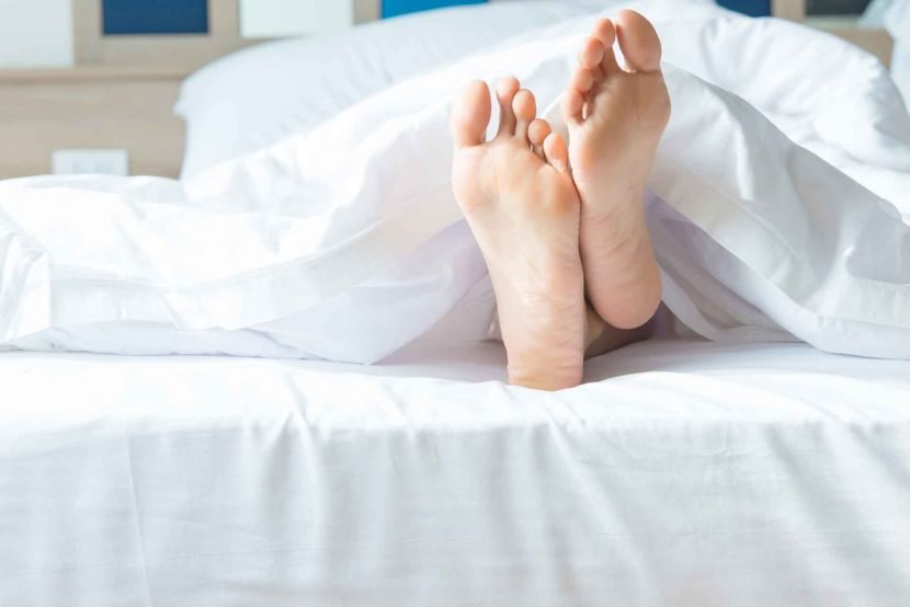 close up of woman's feet sticking out from bed cover