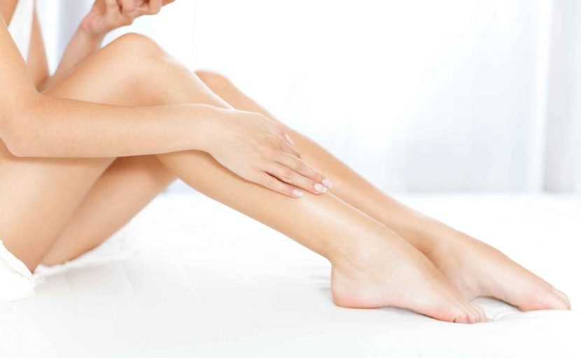 woman sitting on bed touching her right leg