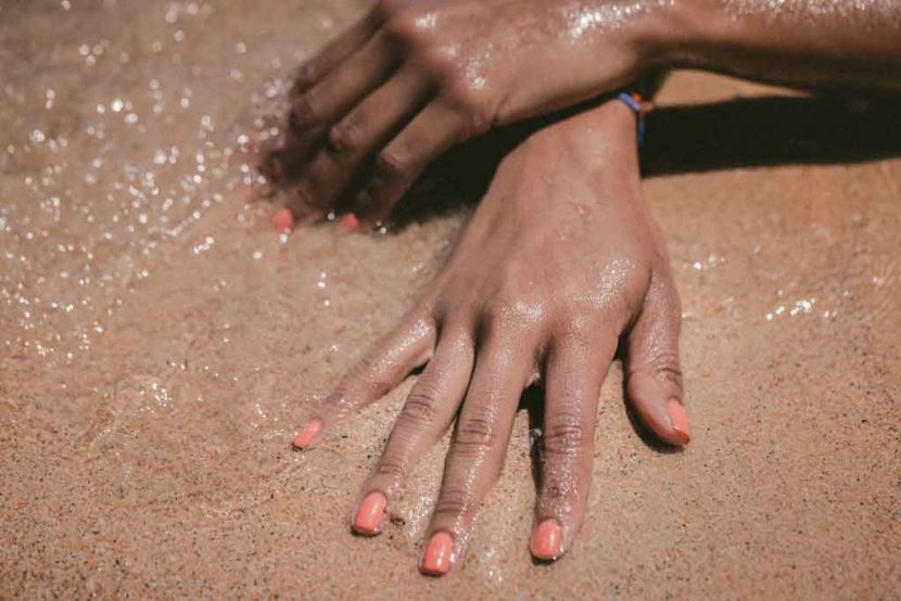 woman's hands in the sand and sea on the beach